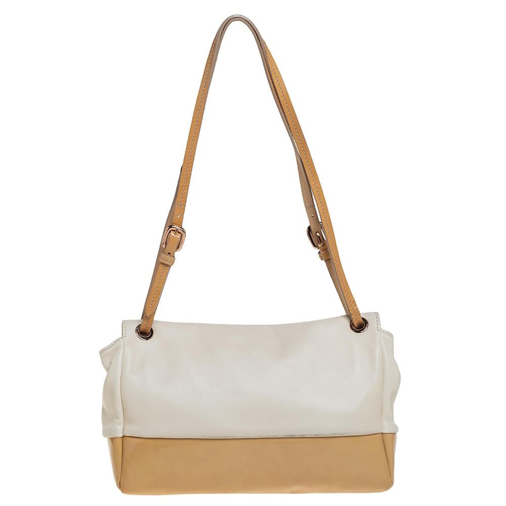 A flap bag in cream leather and beige patent leather highlighted by the signature bow in metal on the front. Held by shoulder straps and lined with fabric, this bag is a fine brew of quality and sophistication. Add a touch of classic charm to your