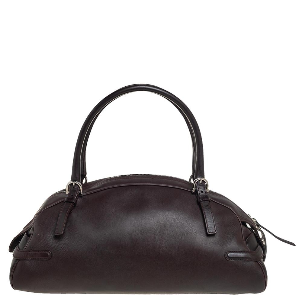 This gorgeous bag by Salvatore Ferragamo will be a fine companion to your style. Skillfully designed, this dark brown bag has the Gancini logo on the flap and two handles on top. It can hold all your essentials with ease in its fabric-lined
