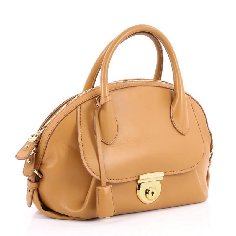This authentic Salvatore Ferragamo Fiamma Satchel Leather Medium, an ode to the classic 1990's Ferragamo design, is sophisticated and elegant. Crafted from camel leather, this heritage-inspired dome satchel features a front flap pocket, dual-rolled