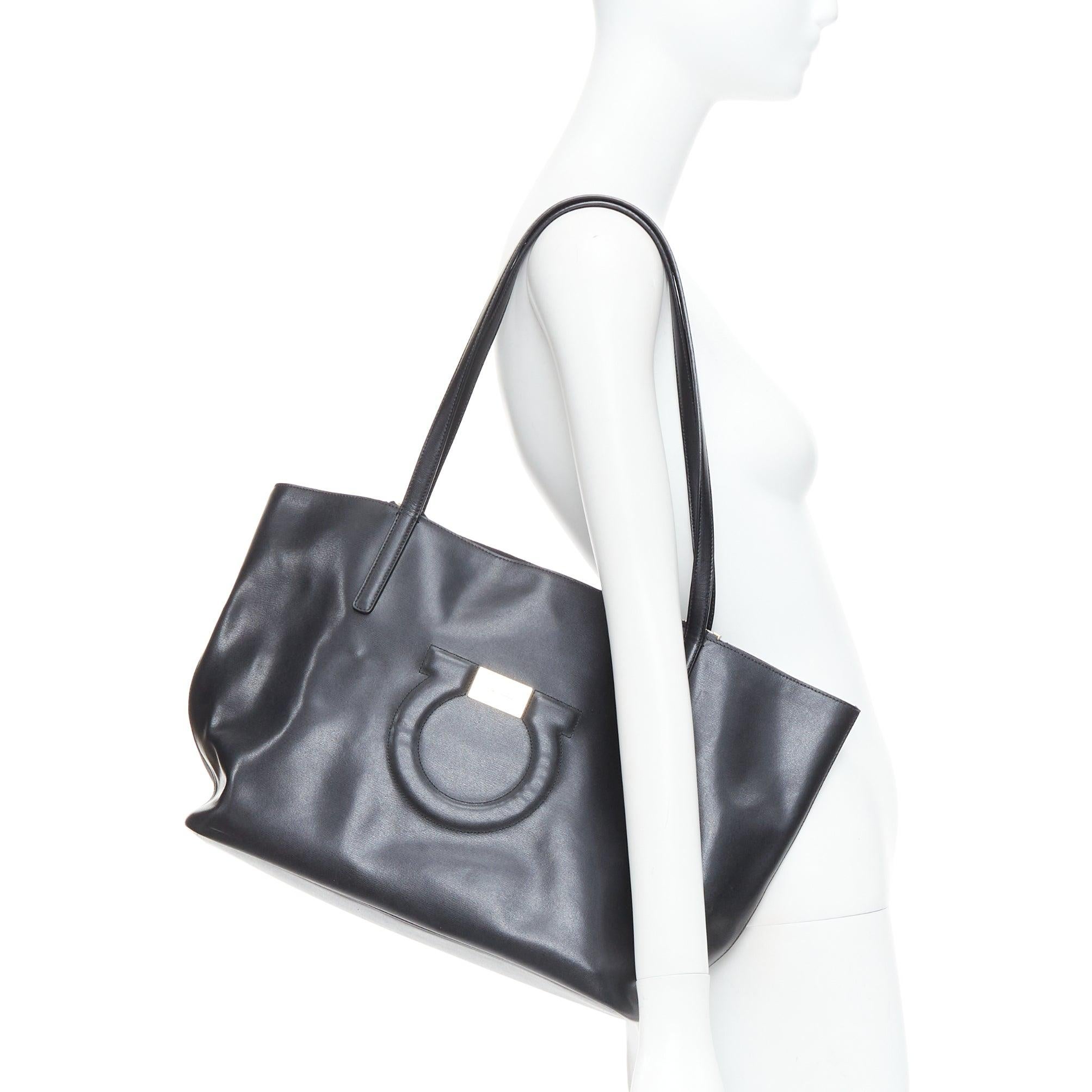SALVATORE FERRAGAMO Gancini black logo gold metal plate shoulder tote bag
Reference: NILI/A00099
Brand: Salvatore Ferragamo
Model: Gancini Tote
Material: Leather
Color: Black, Gold
Pattern: Solid
Closure: Zip
Lining: Black Leather
Extra Details: