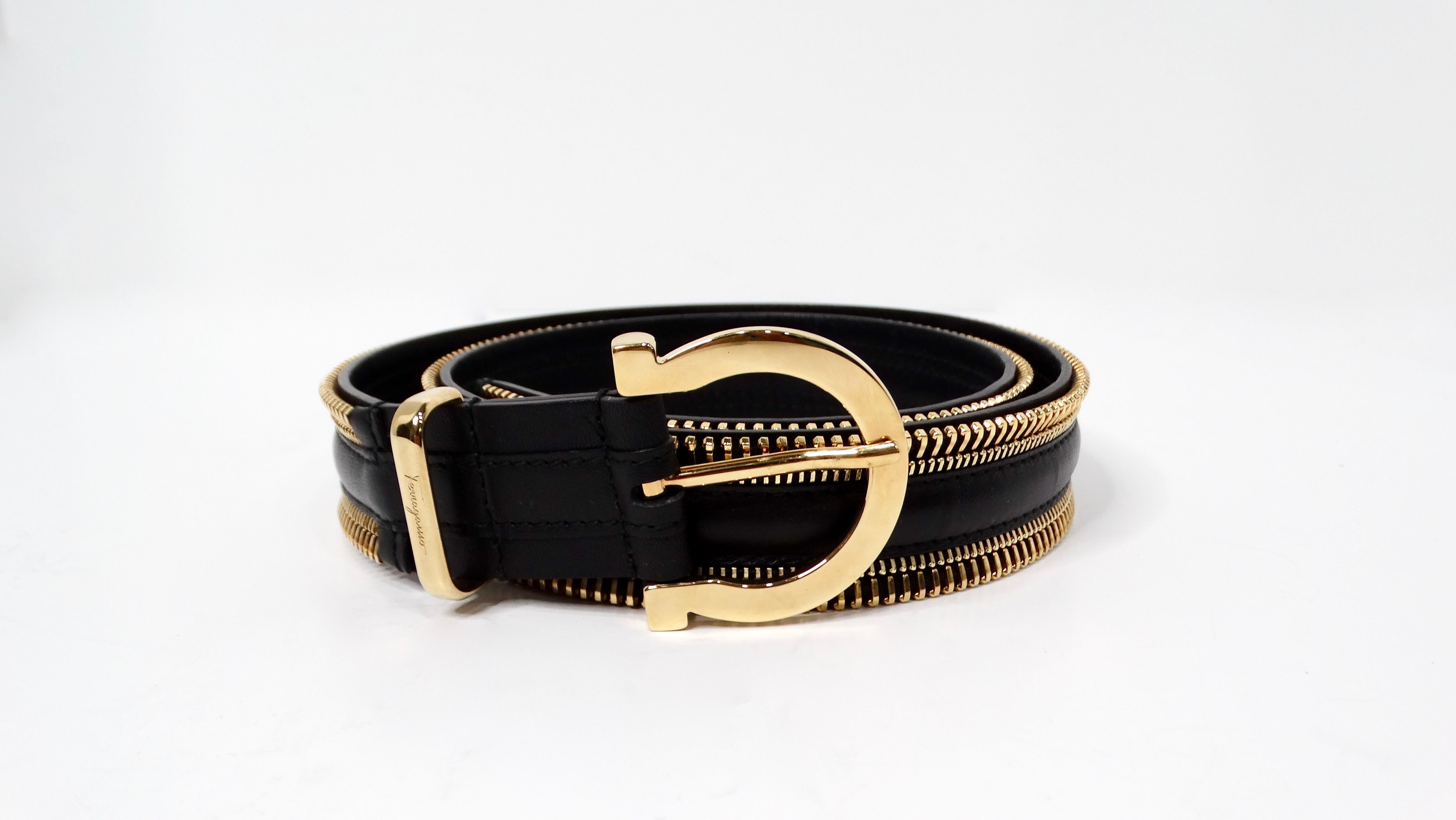 The Salvatore Ferragamo Gancini Gold-Tone Open Zipper Style Black Leather Belt is a striking piece that blends modern luxury with timeless elegance. Crafted from high-quality black leather, this belt is enhanced by a unique gold-tone zipper that