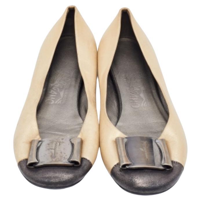 Verleihen Sie Ihren Füßen absoluten Komfort und Entspannung mit diesen Ballerinas von Salvatore Ferragamo. Sie sind aus gold-schwarzem Metallic-Leder gefertigt und mit einer Metallverzierung an den Zehen versehen. Sie haben eine gekappte Zehenpartie
