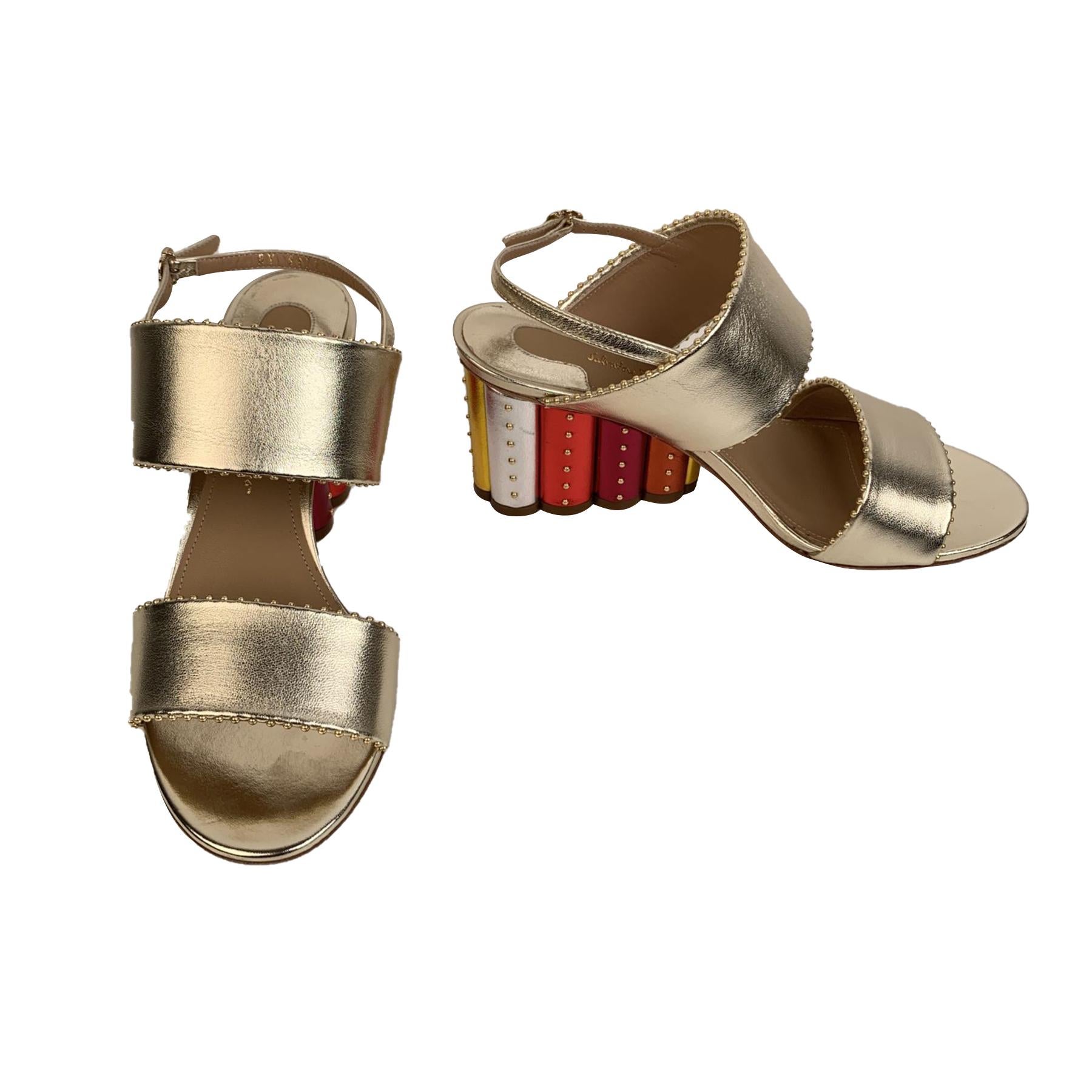 Elegant Salvatore Ferragamo 'Gavi' heeled sandals. Crafted in gold metal leather. They feature peep toe, slingback design, small gold tone studs embellishment along the edges and buckle closure on the ankle. Beautiful Rainbow covered scalloped block