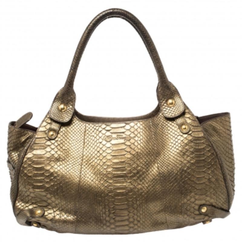 Simply gorgeous and built to endure all your busy days, this Salvatore Ferragamo bag will be the best buy of the year. It has been crafted from gold python and enhanced with a front logo buckle pocket, metal feet, and two handles. The bag is