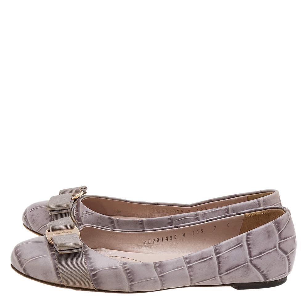 Fashion is the perfect blend of luxury with comfort, and this pair of ballet flats from the house of Ferragamo exudes just that. Crafted from smooth grey croc-embossed leather and styled with their signature Varina bow on the uppers, these flats are