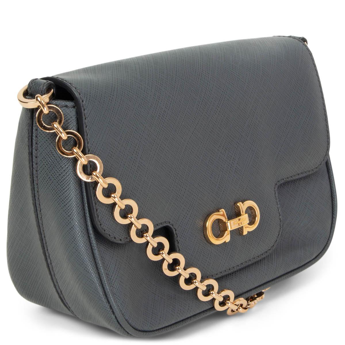 100% authentic Salvatore Ferragamo Luciana mini crossbody bag in grey textured leather featuring gold-tone hardware, a chain link shoulder-strap and a flat pocket at the back. Opens with Double Gancini buckle with a magnetic button under the flap