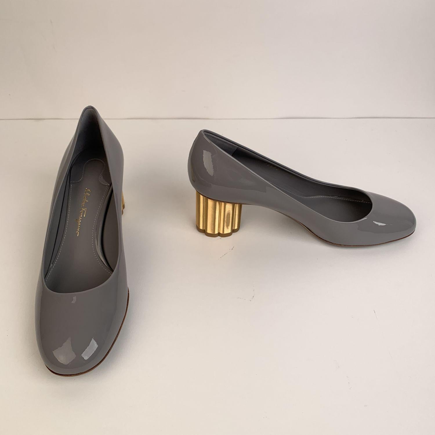 Classic Salvatore Ferragamo Lucca 55 closed toe pumps. Crafted in grey patent leather. They feature round toe, slip on design and gold metal block flower-shaped covered heel. Leather sole. Heels Height: 2.1 inches - 5.5 cm. Made in Italy. Size: US 7