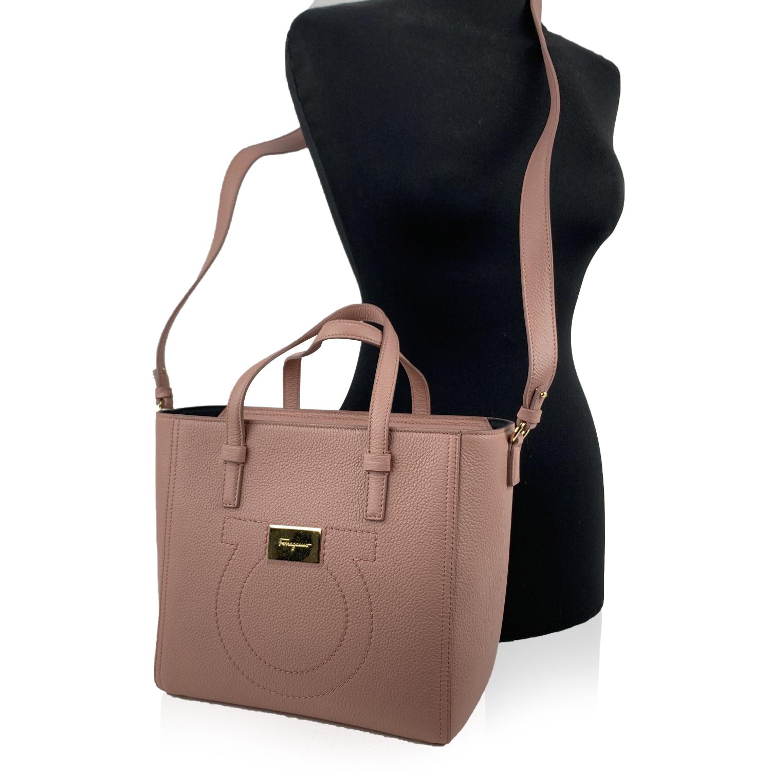 Beautiful shopper 'Marta O' bag by Salvatore Ferragamo. Made of textured pink leather. It features stitched logo detailing and gold metal logo plaque on the front, 4 protective feet, zip closure on top and and black fabric lining . 1 side open