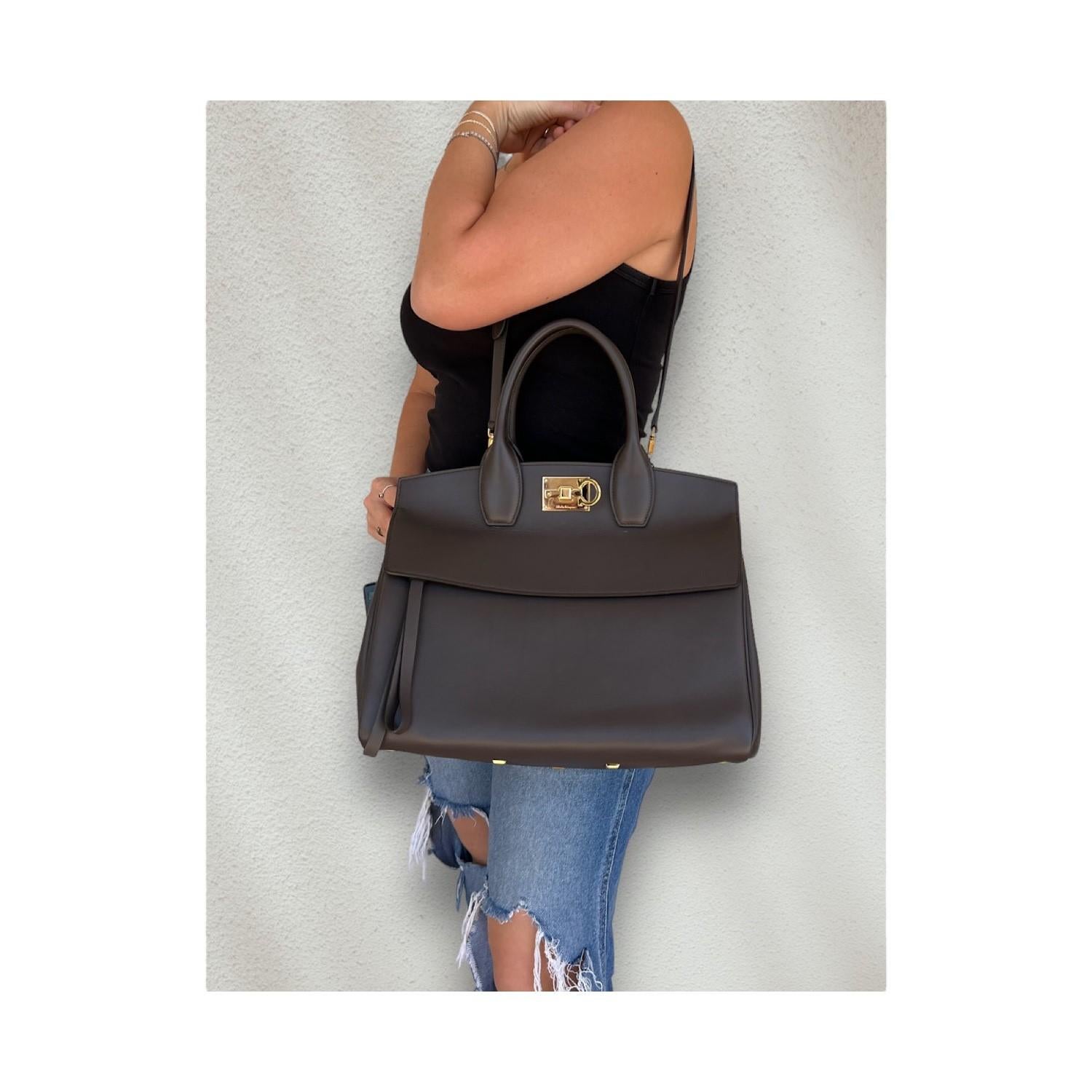 This Salvatore Ferragamo Studio Bag was made in Italy and it is crafted of grey natural-grain calfskin leather and gold-tone hardware features. It has a frontal zipper pocket and it also has an adjustable and removeable shoulder strap. It features a