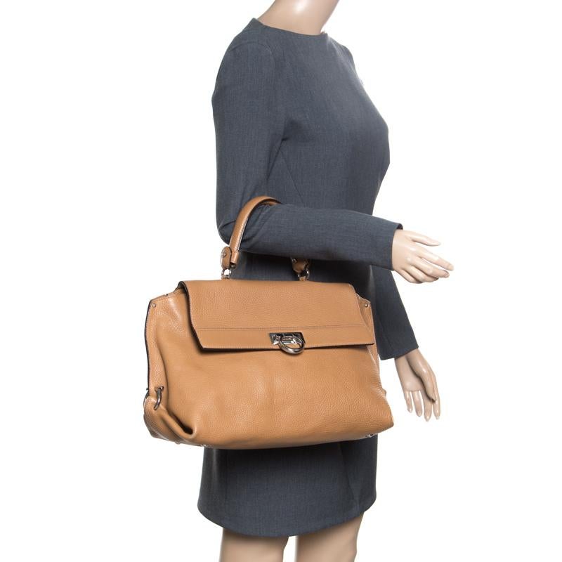 Carry this gorgeous Salvatore Ferragamo creation wherever you go and make people drool. Meticulously crafted from leather, this satchel has been styled in a light brown hue and equipped with a top handle, protective metal feet, and a nylon interior