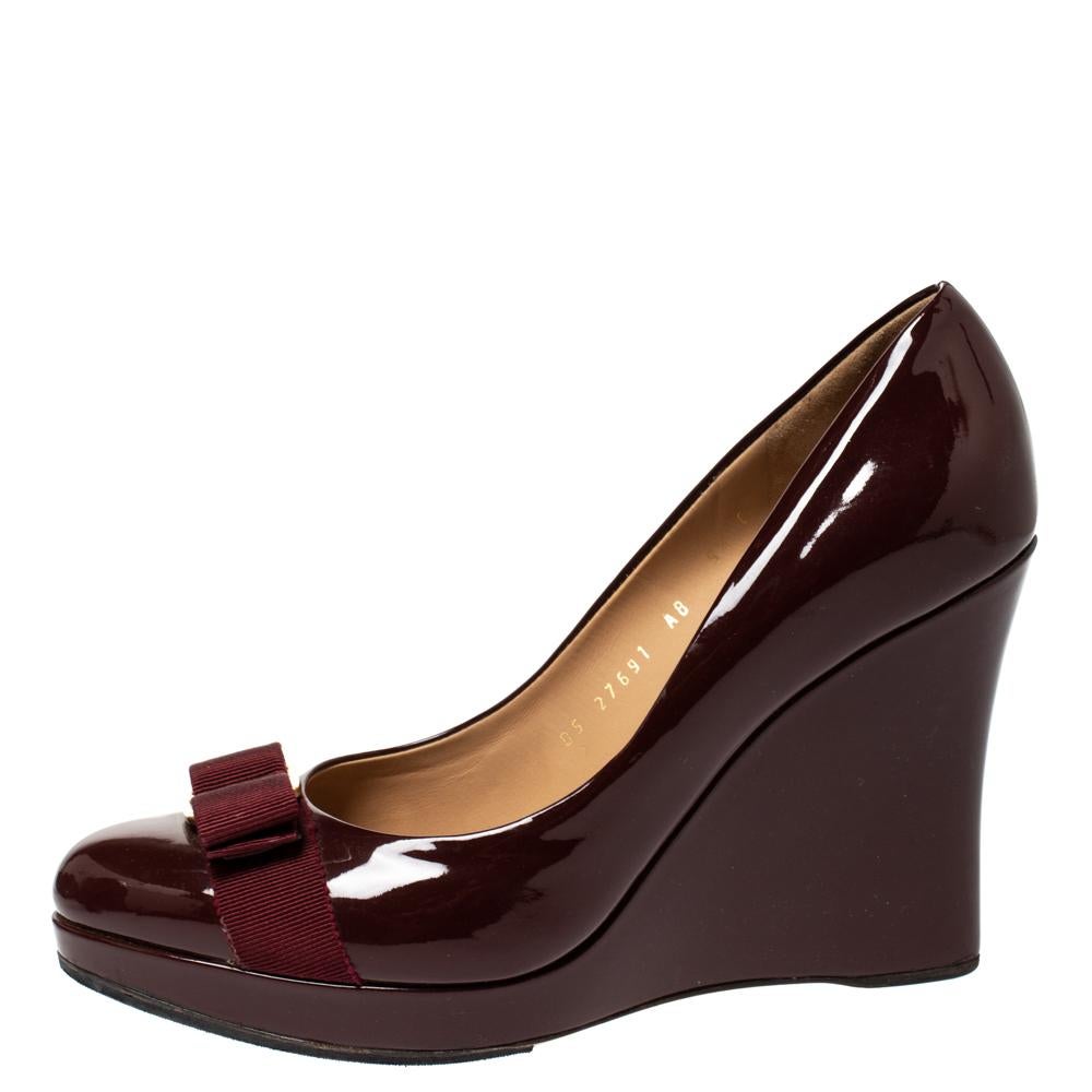 Comfort and style are what these Ferragamo pumps embody! Crafted from patent leather in a splendid maroon shade, these sleek wedge pumps feature delightfully comfy insoles housing the brand's iconic label. Complete with the signature Vara bow, these