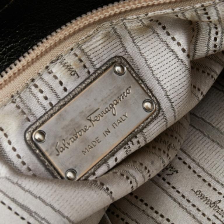 Confectionné en cuir, ce fourre-tout Salvatore Ferragamo vert olive métallisé présente un extérieur au design étonnant et un intérieur spacieux en tissu. Le sac est équipé de deux poignées et de pieds métalliques de protection. Cette beauté, bien