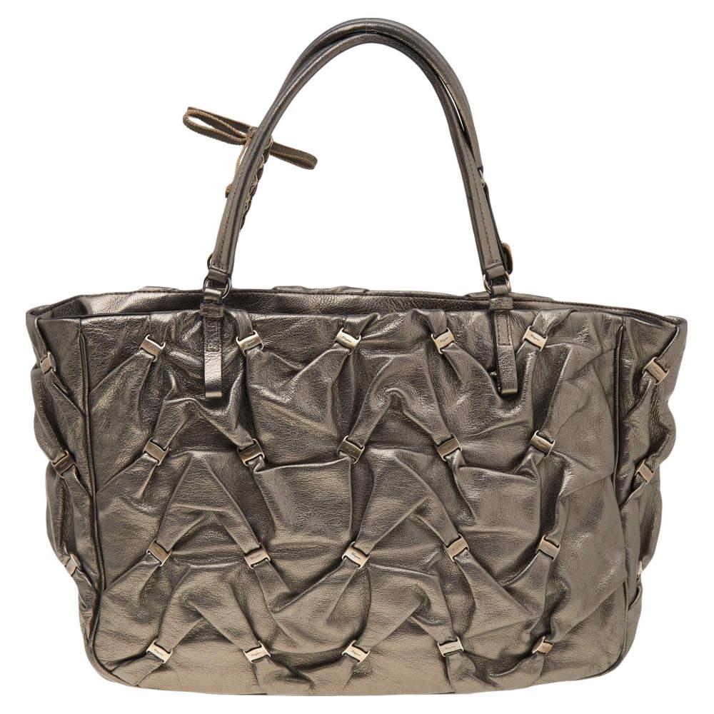 Crafted from leather, this metallic olive green Salvatore Ferragamo tote has an amazingly-designed exterior and a spacious fabric interior. The bag is equipped with two handles and protective metal feet. Swing this beauty on your busy days as it is