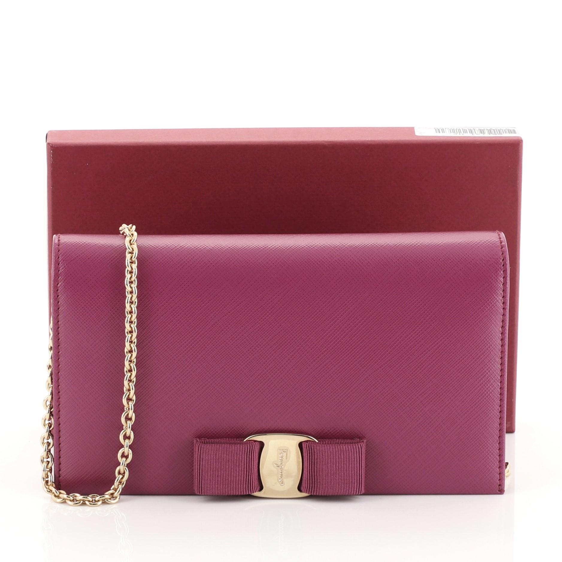 This Salvatore Ferragamo Miss Vara Chain Wallet Saffiano Leather, crafted in purple saffiano leather, features the Vara pleated bow design, long chain strap and gold-tone hardware. Its hidden magnetic snap closure in its flap opens to a purple