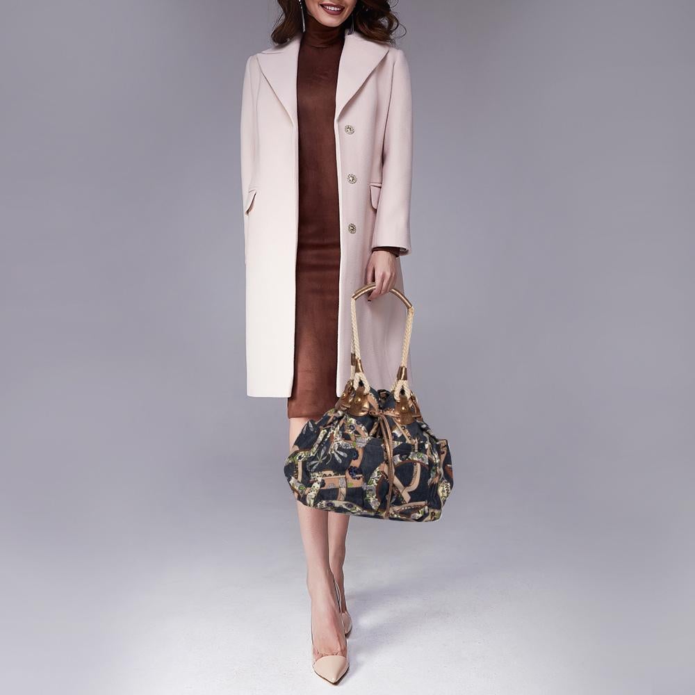This Salvatore Ferragamo handbag is an example of the brand's magnificent designs fused with timeless fashion. Add a stylish touch to your look with this bag. It has the Gancini-floral printed denim, dual handles, and a spacious fabric
