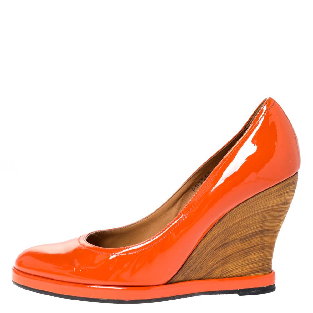 Rock your outfit with these Salvatore Ferragamo pumps. They have been meticulously crafted in Italy and are made from quality patent leather. They come in a lovely hue of orange. They feature round toes, 10.5 cm wedge heels, and a covetable