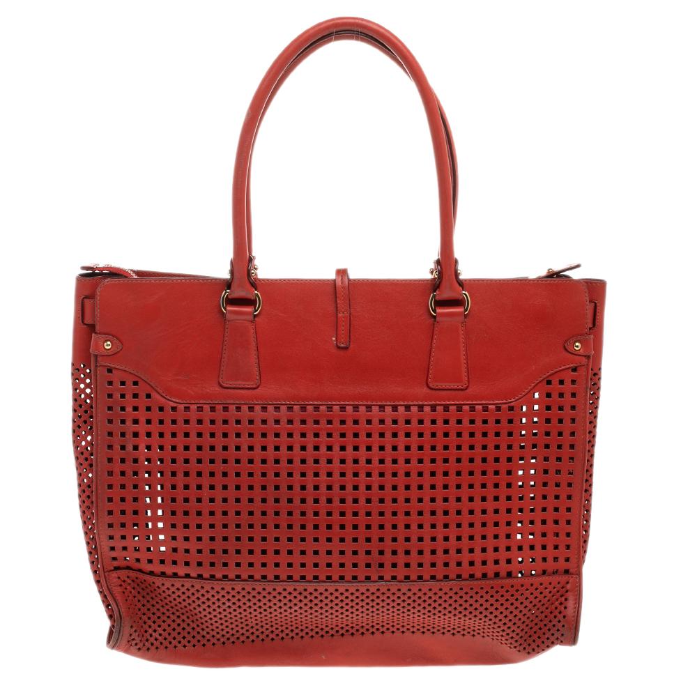 Crafted from perforated leather, this orange Salvatore Ferragamo tote has a little lock-in flap and a spacious leather interior. The bag is equipped with two handles and protective metal feet. Swing this beauty on your busy days as it is well-made