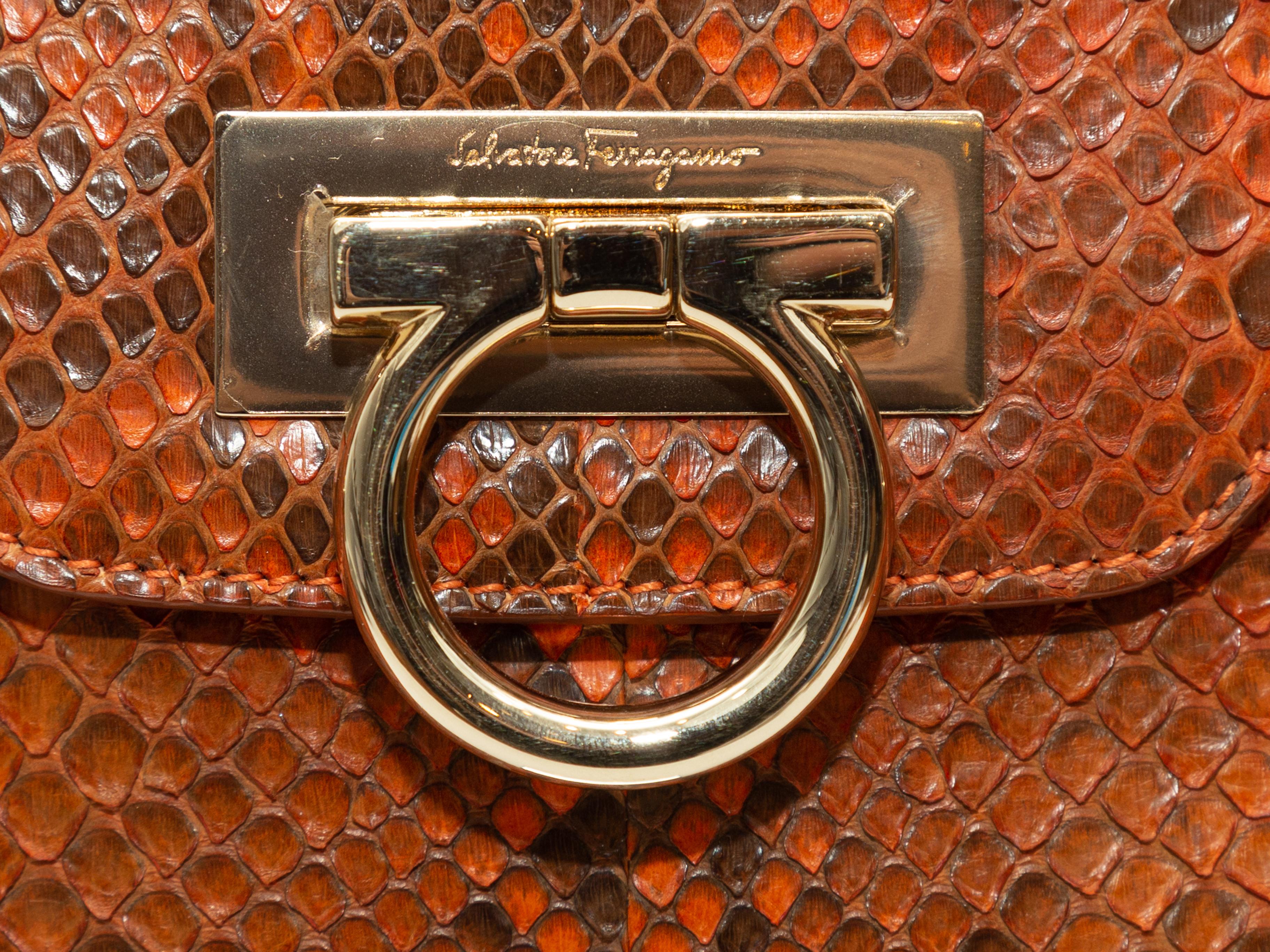 Product Details: Orange python handbag by Salvatore Ferragamo. Gold-tone hardware. Dual rolled top handles. Buckle accents at exterior sides. Gancini closure at front flap. 12.5