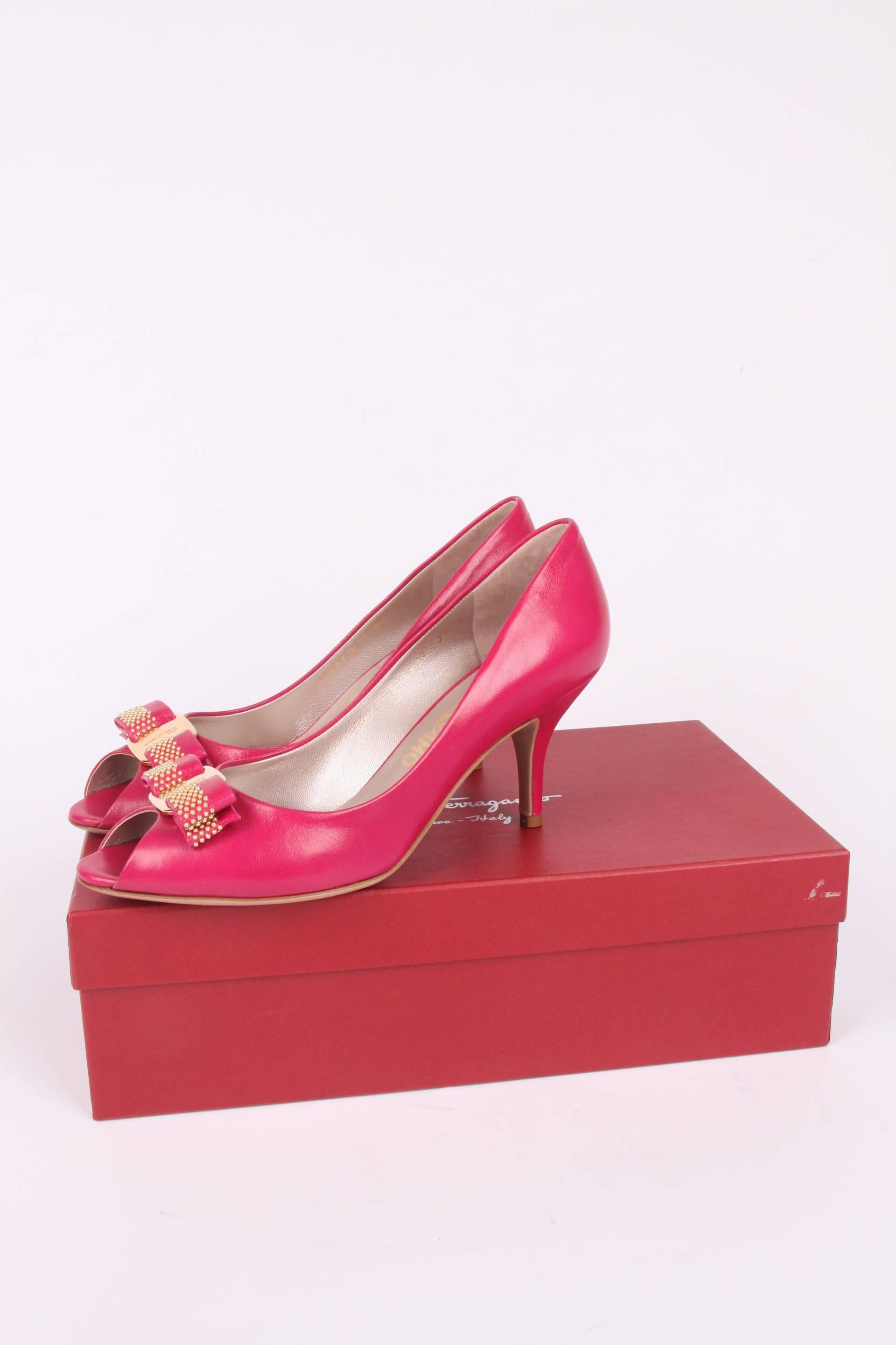 Cheerful pumps by Salvatore Ferragamo crafted in shocking pink leather.  

A peep-toe with a bow and a shiny gold-tone metal plaque with embossing of a Ferragamo logo. Leather outsole and a heel that measures 8 centimeters. Leather insole. 

New and