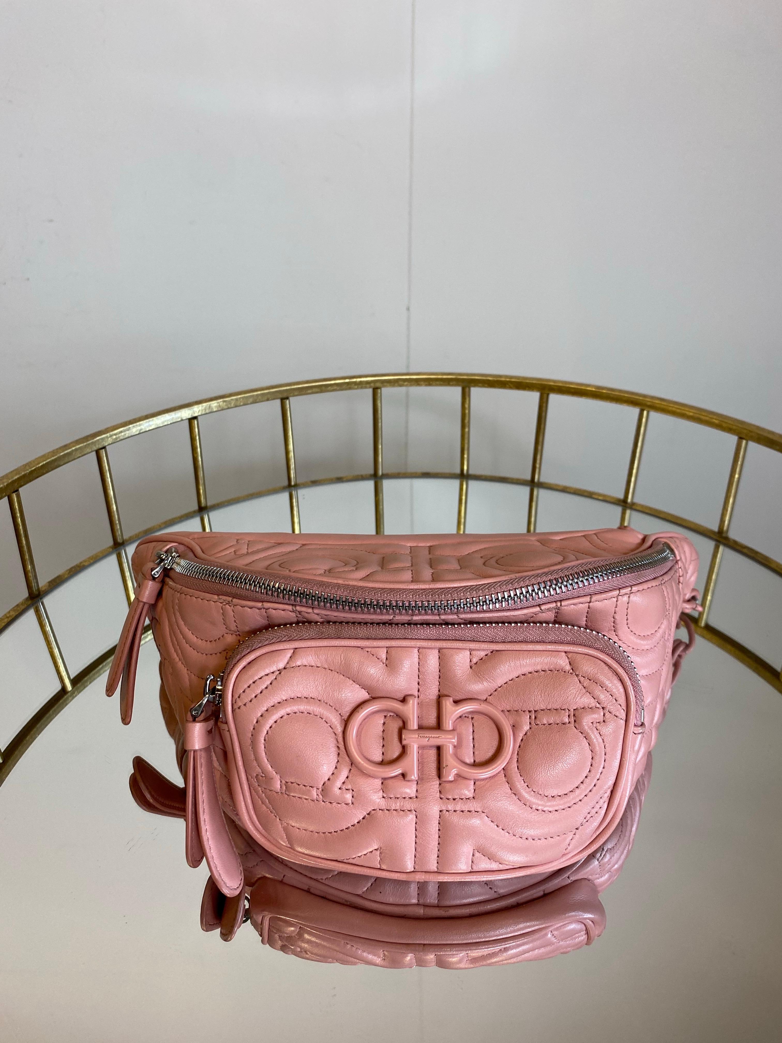 Riñonera Salvatore Ferragamo.
En piel rosa y herrajes plateados.
La pintura de las cadenas falta en varios sitios, como se ve en la foto.
Altura aproximada 16 cm
Anchura aproximada 35 cm
La correa para el hombro es ajustable.
Buen estado general,