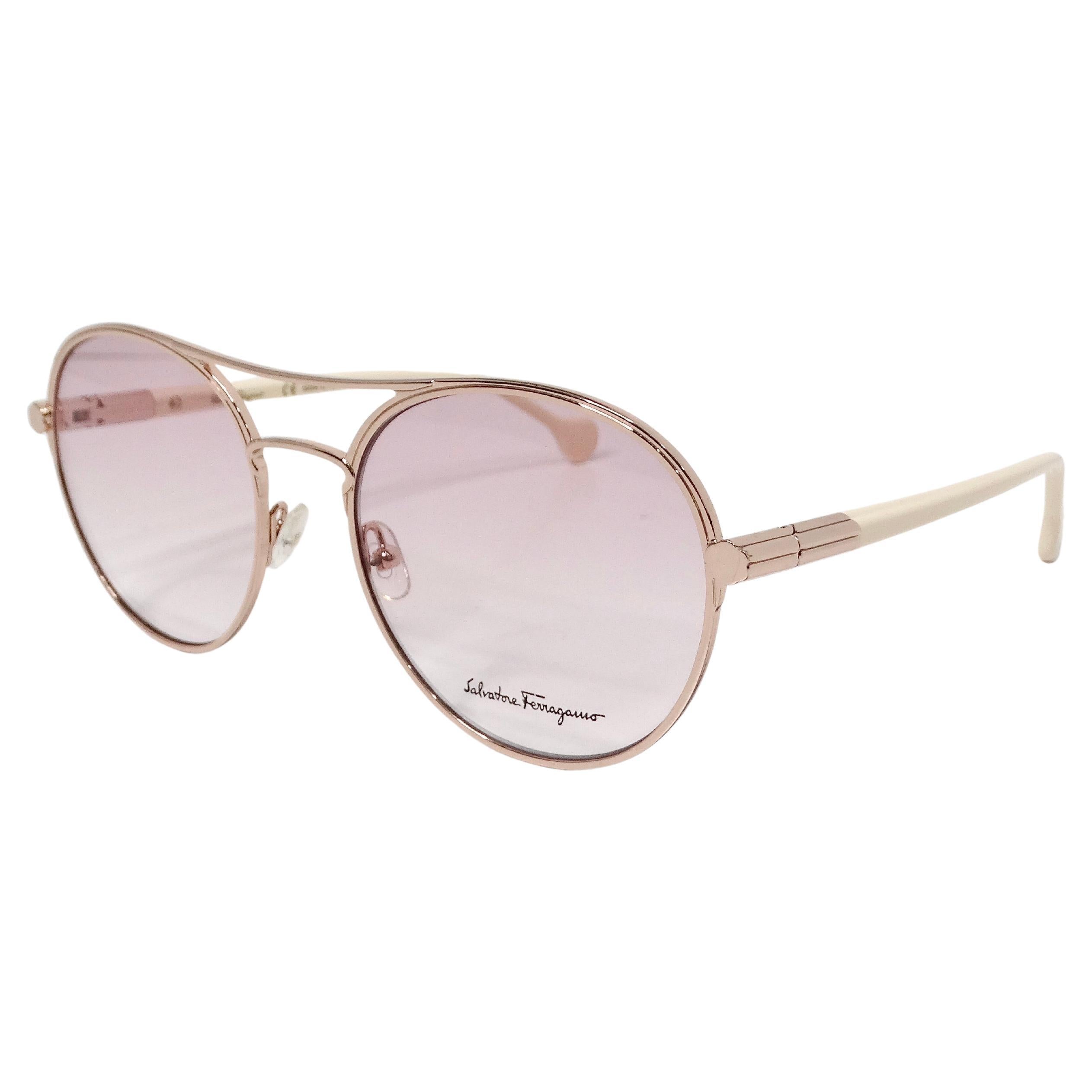 The Salvatore Ferragamo Pink Tinted Gold Tone Frame Aviator Sunglasses epitomize luxury and sophistication, blending timeless design with a modern touch. Crafted with a gold-tone metal frame, these sunglasses feature a subtle pink tint on the