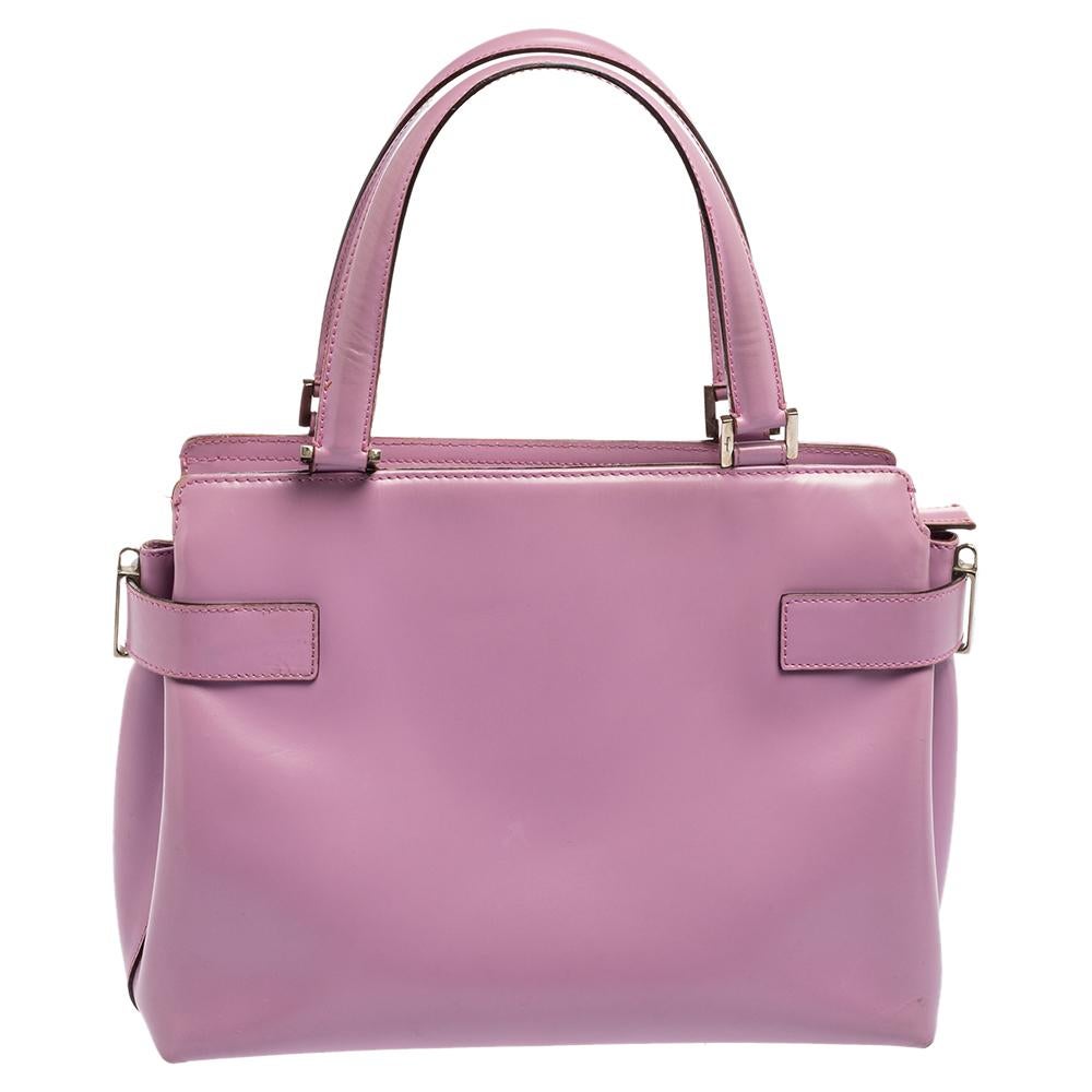 Salvatore Ferragamo brings you this gorgeous buckle tote that has been crafted from purple leather. It comes with two handles, a shoulder strap, a spacious interior, and protective metal feet. The summery bag is complete with complementing