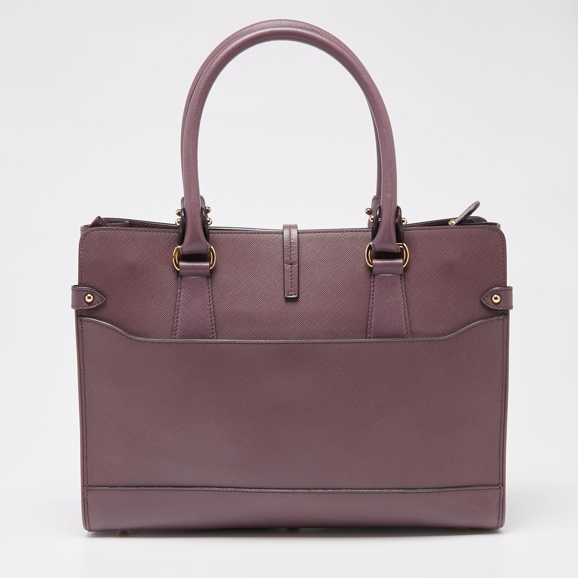 An example of high fashion and elegance is this Salvatore Ferragamo tote. It is made from leather and flaunts a purple shade that is truly mesmerizing. The bag is finished with a simple structure, dual handles, and protective metal feet. It is the