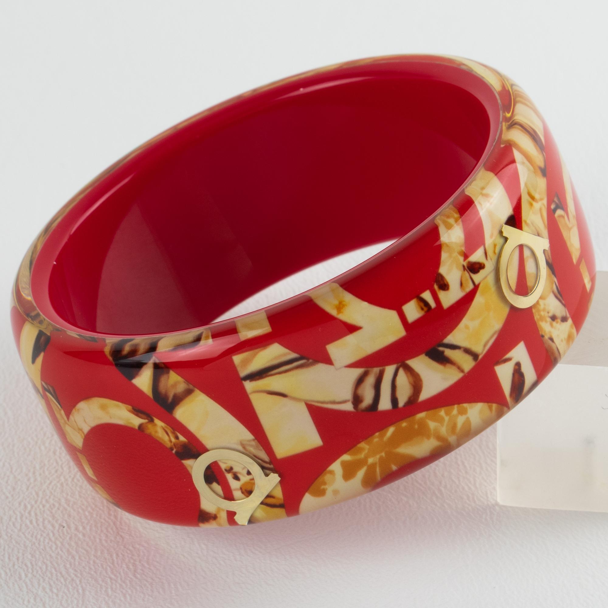 This stunning Salvatore Ferragamo, Italy bracelet features a chunky Lucite or acrylic bangle in luminous red color, ornate with faux-wood textured print and the iconic two-shoe horse company logo emblems in gilded metal, all embedded in the