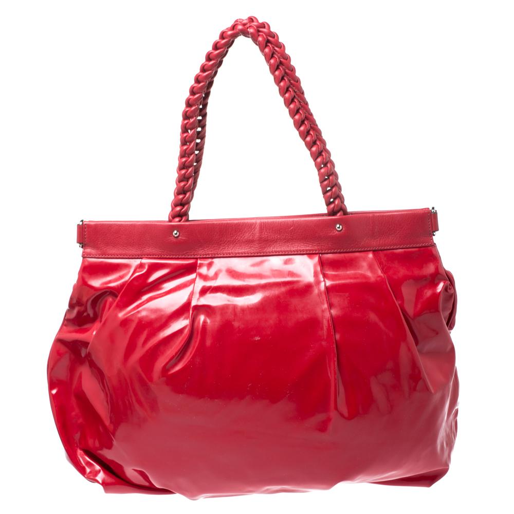 This fashionable bag by Salvatore Ferragamo is all you need to perfectly complement your attire. Crafted in Italy, this hobo bag is made of glossy patent leather and it comes in a stunning shade of red. This statement bag is held by a beautifully