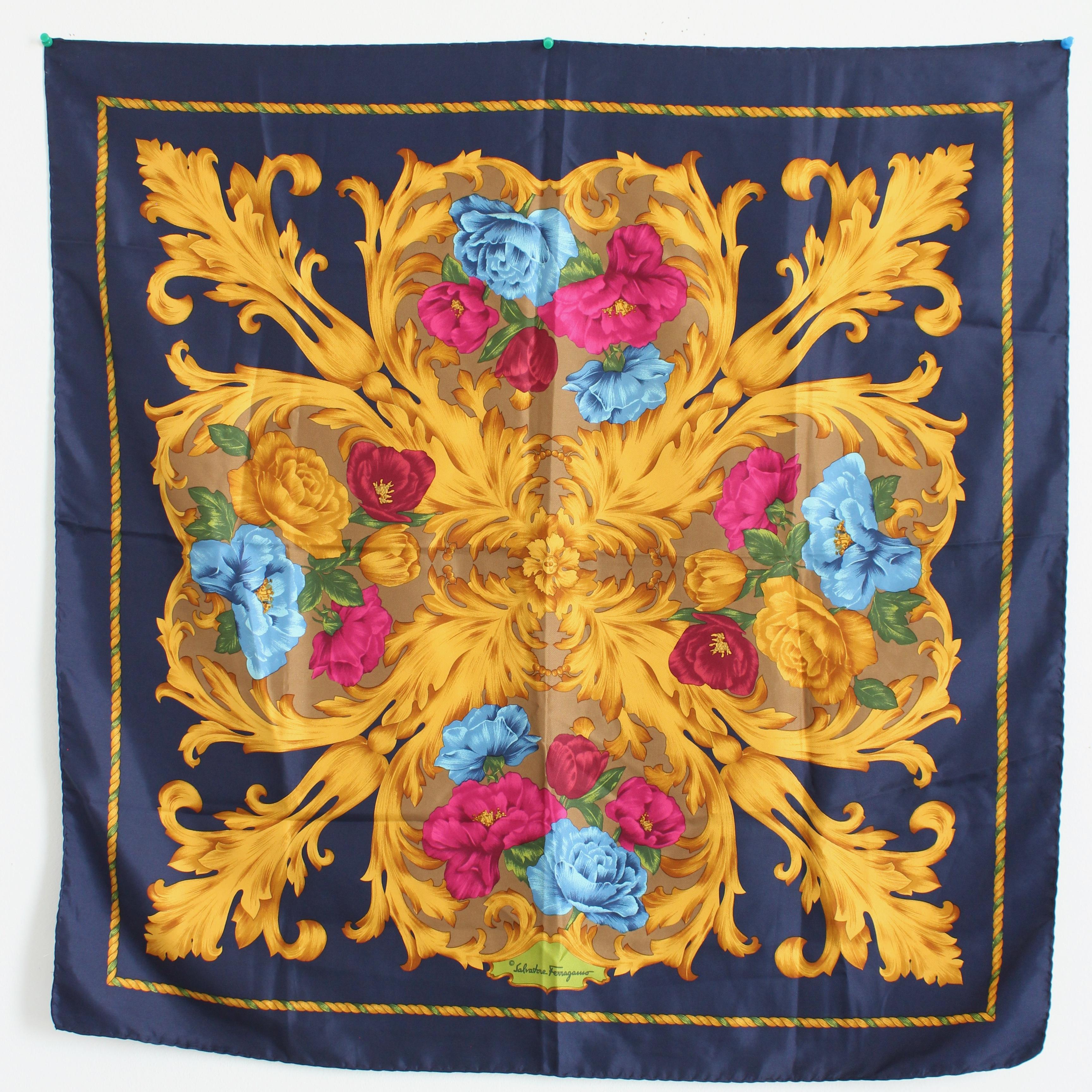 Ce foulard ou châle en soie a été réalisé par Salvatore Ferragamo, très probablement dans les années 90. Il présente des fleurs colorées roses, bleues et rouges avec des tiges dorées de style baroque sur un fond bleu marine. 

Un fabuleux foulard en