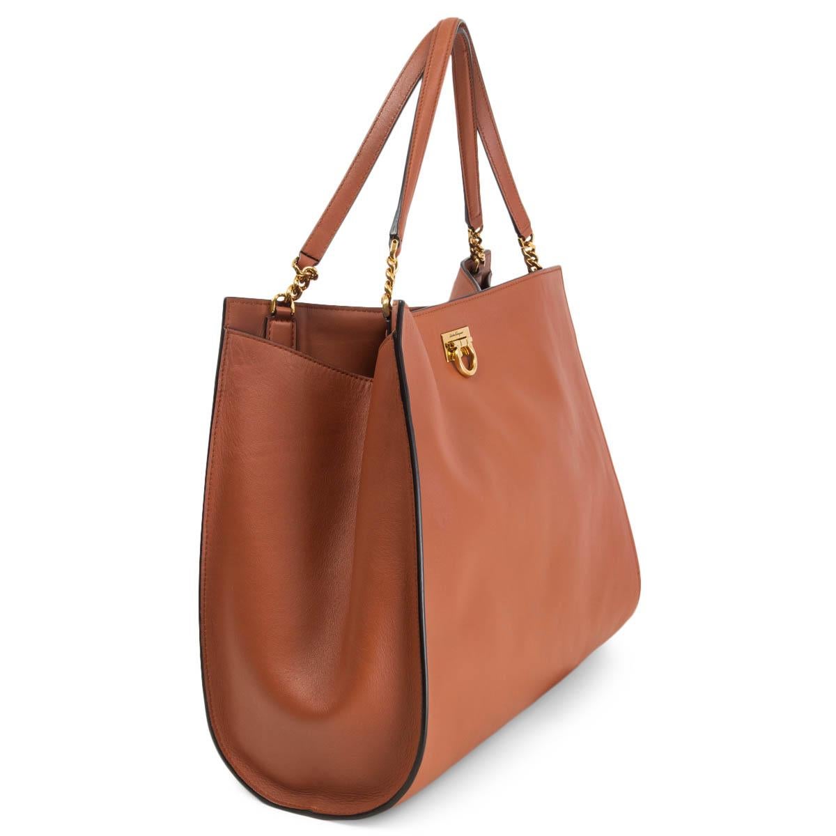 100% authentic Salvatore Ferragamo Trifolio Tote in siena brown soft, matte Italian calf leather. The interior is lined in brown leather with a removable pouch and three flat pockets against the back. The clasp has metal hooks in an antique golden