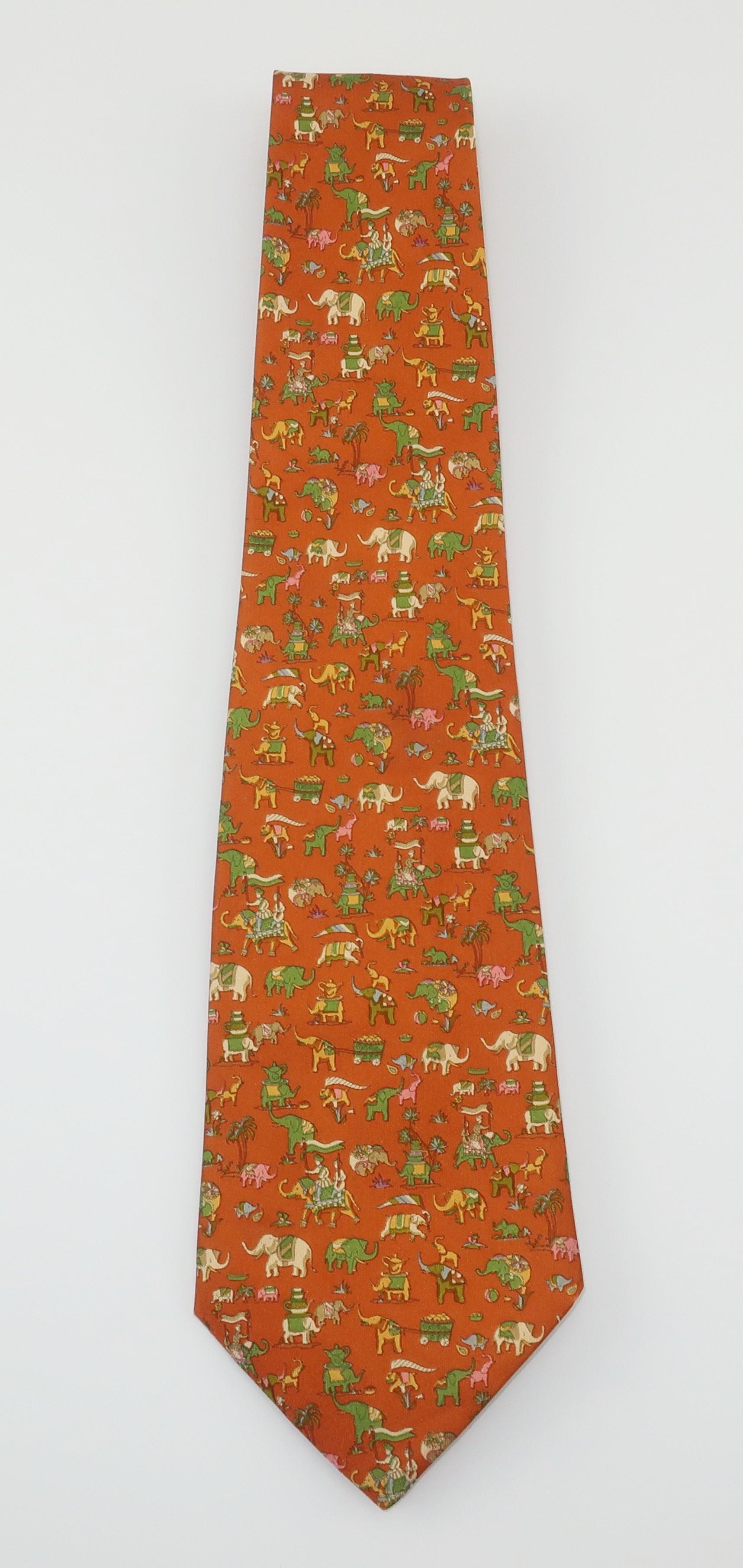 Ferragamo creates a menswear silk necktie with a whimsical Raj motif depicting festooned elephants in shades of green, yellow, pink and antique white all on a pumpkin color background. Beautifully made with the quality one would expect from