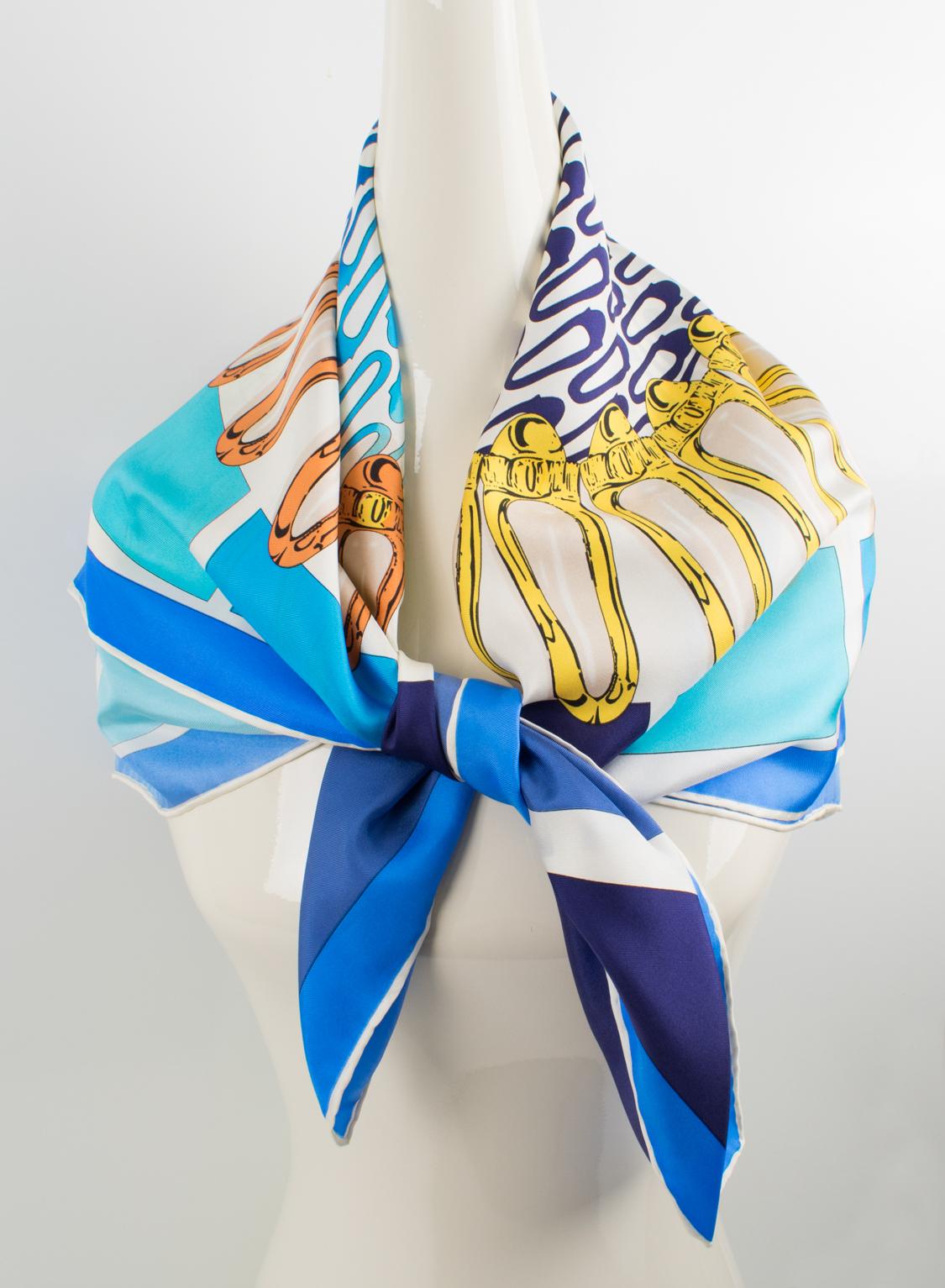 Refined silk scarf by Salvatore Ferragamo in blue hues and assorted colors featuring flat sleeper shoes design print. Salvatore Ferragamo's signature name on the middle center low. The colors are bright and vibrant with a combination of cerulean