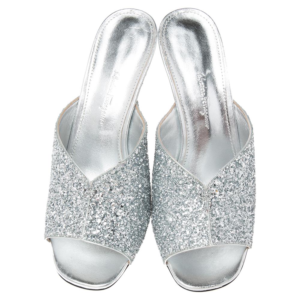 Look highly appealing and glamorous as you wear these slide sandals from the House of Salvatore Ferragamo! They are made from silver glitter on the exterior and flaunt F-heels and open toes. Beautifully made, these sandals will lend a glam edge to