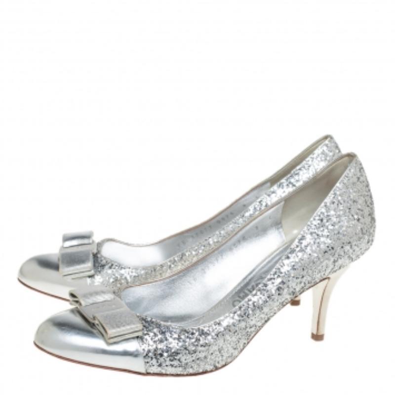 Designed with small heels and a classic color, this pair of Salvatore Ferragamo peep toes is perfect for your evening looks. Their exterior is made from glitter and designed with Vara bows on the toe caps with logo-embossed silver-tone plates. Lined