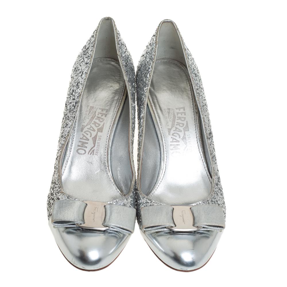 Designed with small heels and a classic color, this pair of Salvatore Ferragamo peep toes is perfect for your evening looks. Their exterior is made from glitter and designed with Vara bows on the toe caps with logo-embossed silver-tone plates. Lined