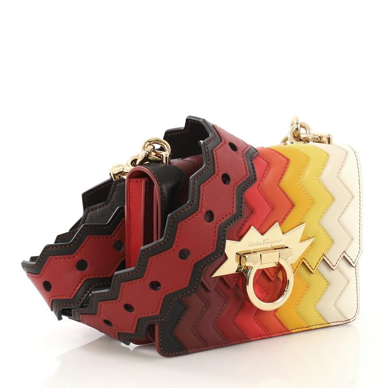 This Salvatore Ferragamo Sindy Rainbow Crossbody Bag Zig Zag Leather Small, crafted from multicolor leather, features chain strap with leather pad, starburst hardware detailing, exterior back slip pocket, and gold-tone hardware. Its gancio closure