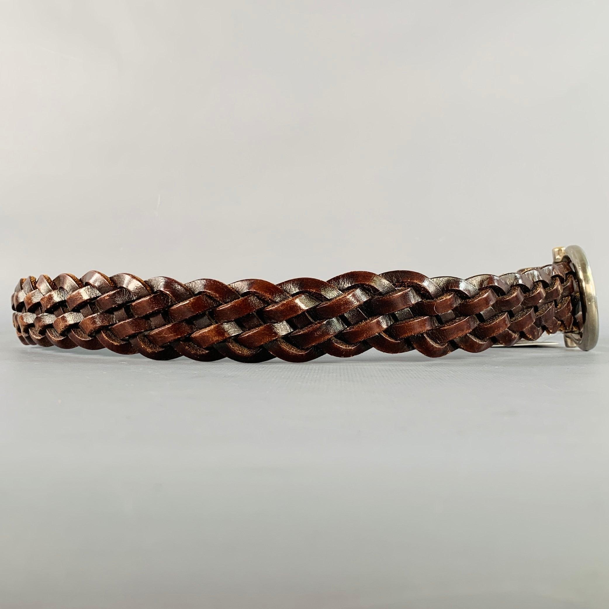 SALVATORE FERRAGAMO
Ceinture en cuir marron foncé, tressée, avec boucle FERRAGAMO argentée. Fabriqué en Italie. Très bon état. Signes d'usure sur la boucle. 

Marqué :   CS-37 6539Longueur : 44.5 pouces Largeur : 1.25 pouces Convient : 34 pouces  -