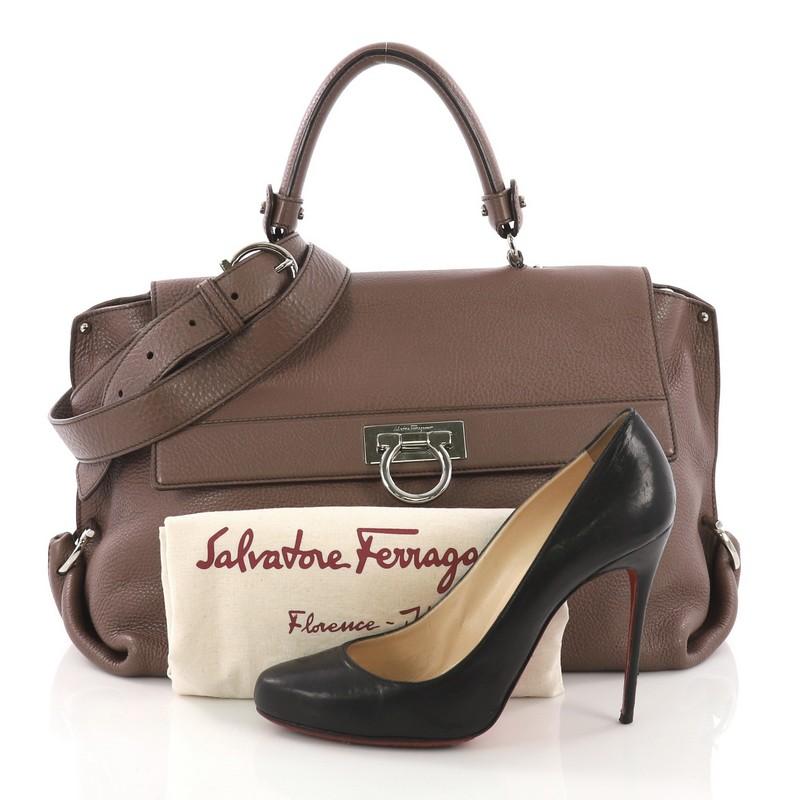 This Salvatore Ferragamo Sofia Satchel Grainy Leather Large, crafted in brown grainy leather, features a top leather handle, exterior back zip pocket, side gancini detailing, and silver-tone hardware. Its top flap with flip-lock Gancio and zip