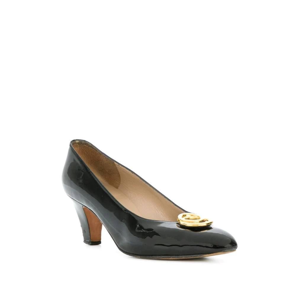 Salvatore Ferragamo 80s black patent leather pumps. Almond toe with gold-tone metal rings decorative appliqué. Medium heel.

Size: 38 IT

Measurements
Heel height: 6 cm
Insole length: 24,5 cm

Product code: A8132

Notes: The item shows signs of wear