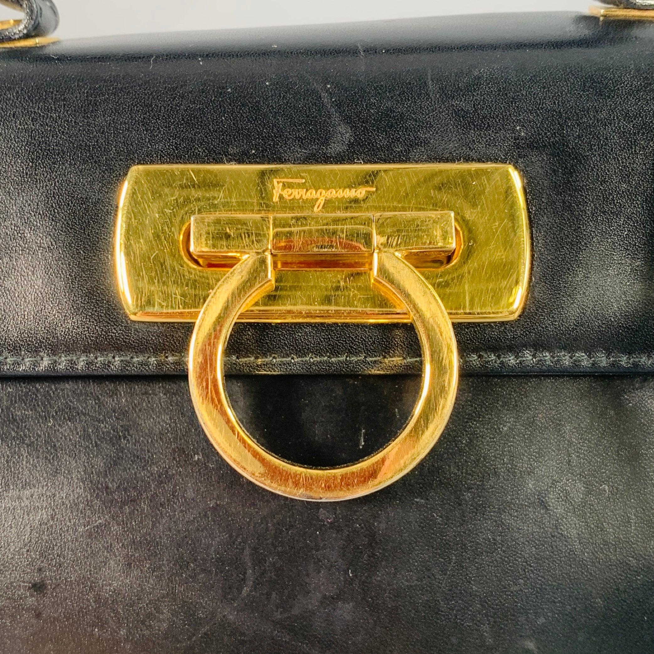 Vintage SALVATORE FERRAGAMO Handtasche
aus schwarzem Leder mit Henkeln an der Oberseite, abnehmbarem Querriemen und goldfarbenem Metallverschluss mit Hufeisen. Wird mit Staubbeutel geliefert. Made in Italy. sehr guter Vintage-Zustand. Leichte