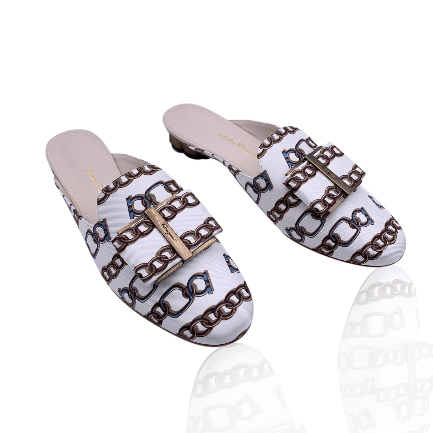 Sophisticated Salvatore Ferragamo 'Sciacca Twill' mules. Crafted in white silk twill with chain print, they feature a slip-on design, round toe, bow detailing on the toes and antiquated gold metal block flower-shaped low heel (height: 1 cm). Leather
