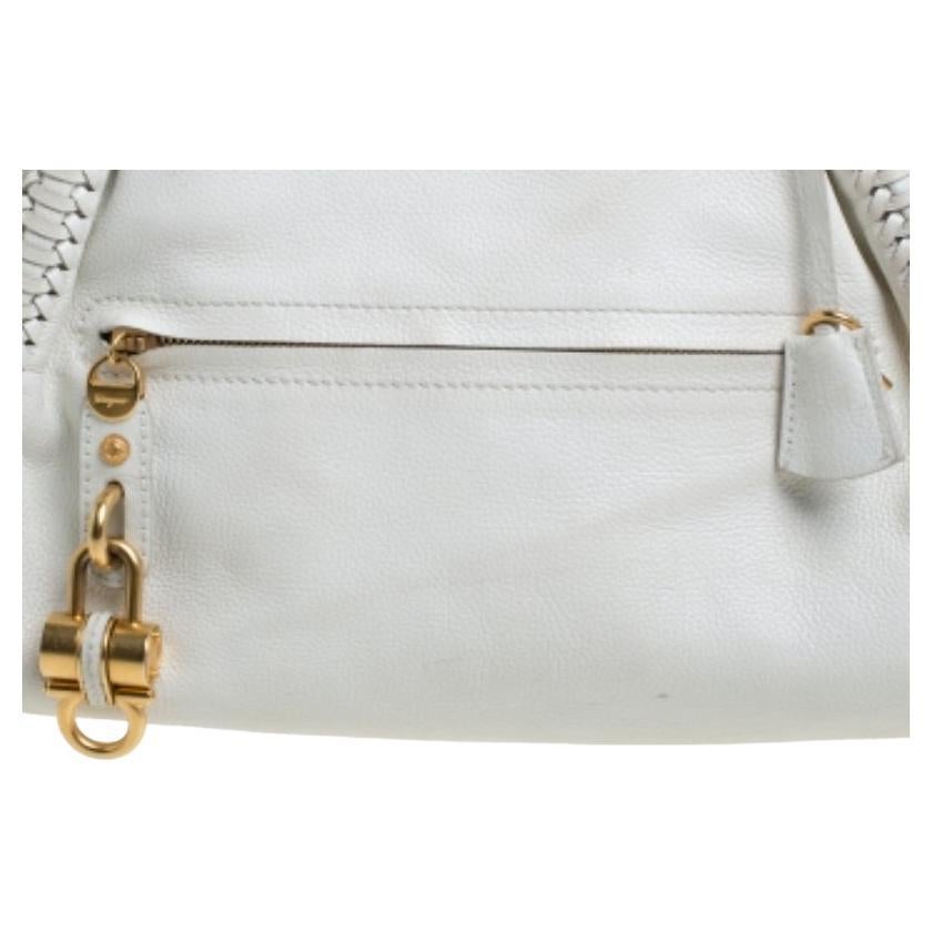 This Salvatore Ferragamo satchel will help you put together a chic urbane look. Flaunting a splendid white hue, the fabric-lined interior will help you accommodate all your essentials safely. It is complete with a front zip pocket and two leather