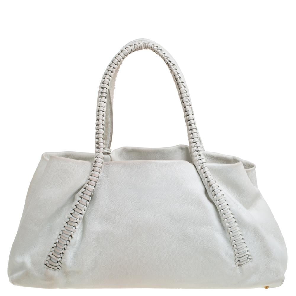 This Salvatore Ferragamo satchel will help you put together a chic urbane look. Flaunting a splendid white hue, the fabric-lined interior will help you accommodate all your essentials safely. It is complete with a front zip pocket and two leather
