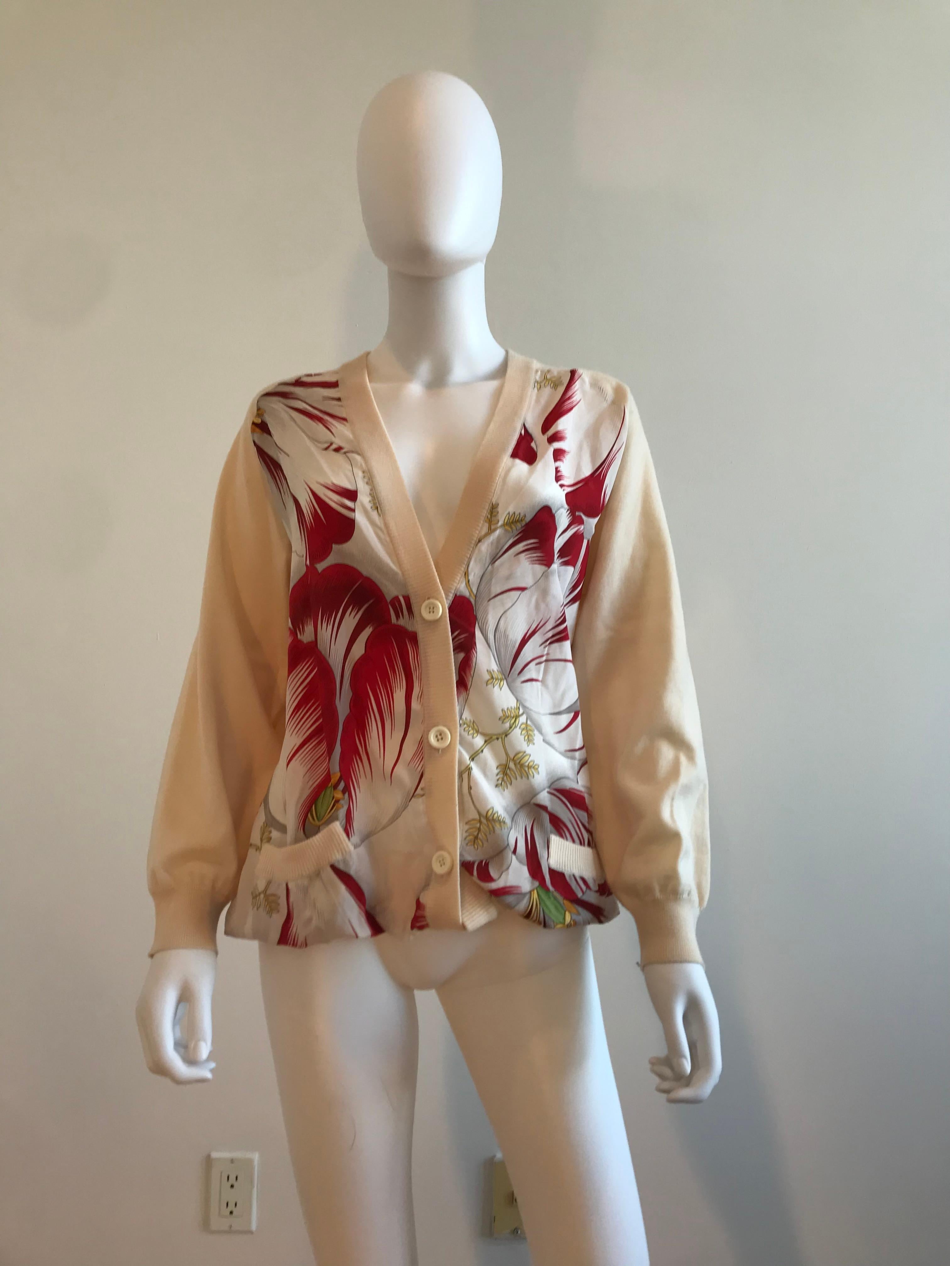 This vintage Salvatore Ferragamo cardigan sweater has front panels of printed silk in a tropical scarf print that includes flowers, leaves, and abstract floral prints with pale taupe wool knit fabric back, sleeves and trim.
Size