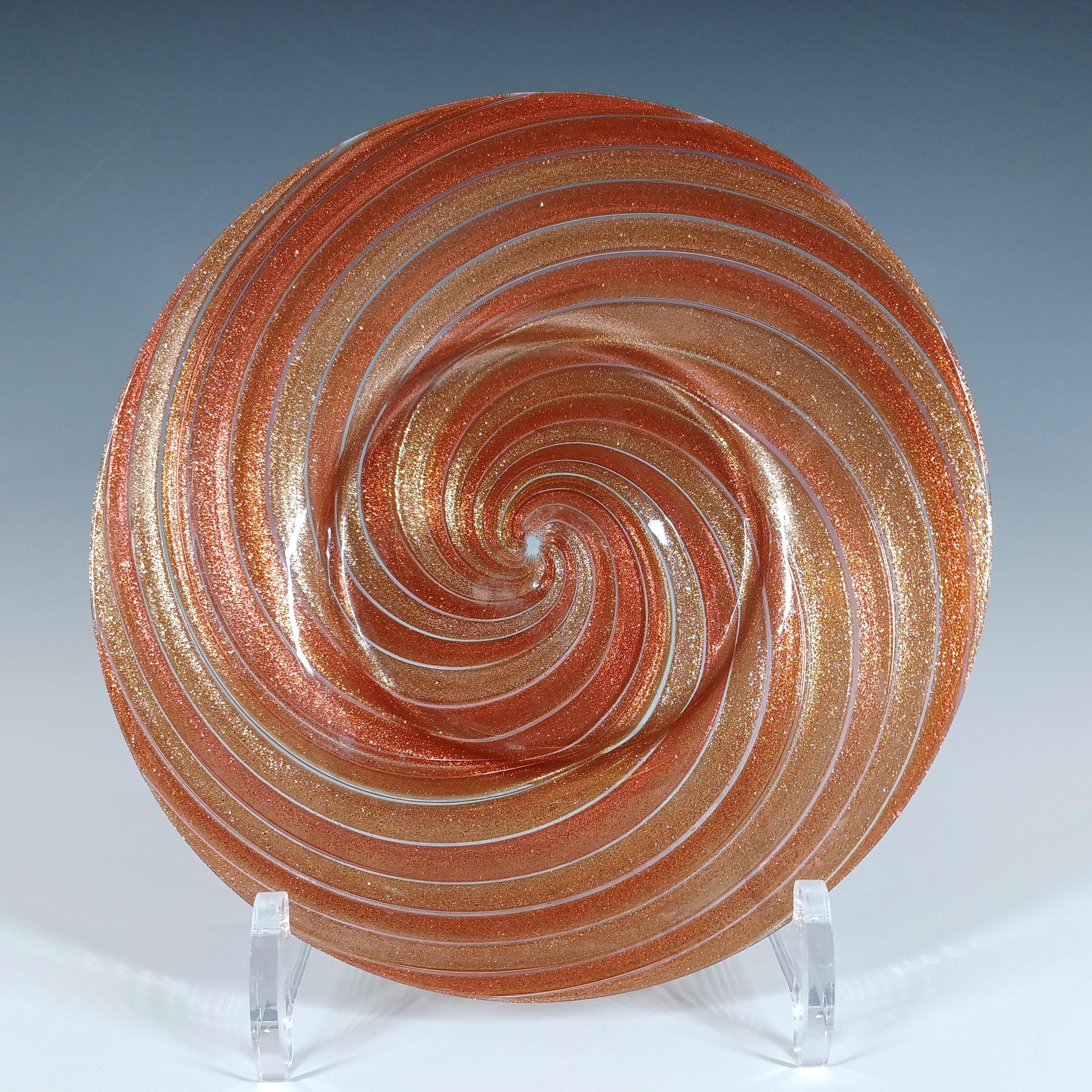 Voici une magnifique assiette / plat en verre vénitien, fabriqué sur l'île de Murano, près de Venise, en Italie. Décoré de bandes en spirale en aventurine de cuivre. Fabriqués par Salviati, des objets similaires sont présentés dans le livre 