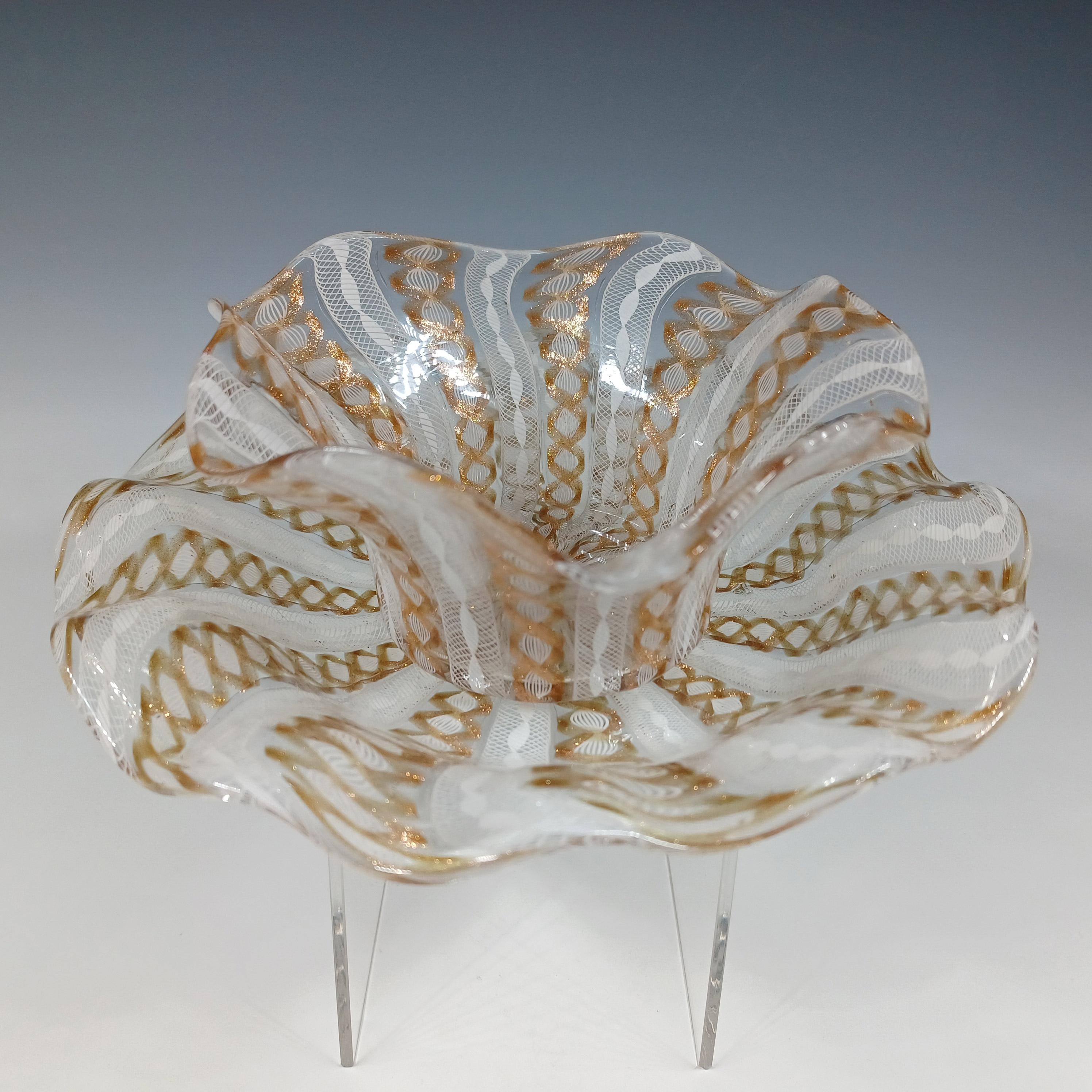 He aquí un maravilloso juego de cuenco y plato de vidrio veneciano, fabricado en la isla de Murano, cerca de Venecia, Italia. Decorada con franjas alternas de filigrana de celosía de zanfirico blanco, algunas ribeteadas de aventurina cobriza.