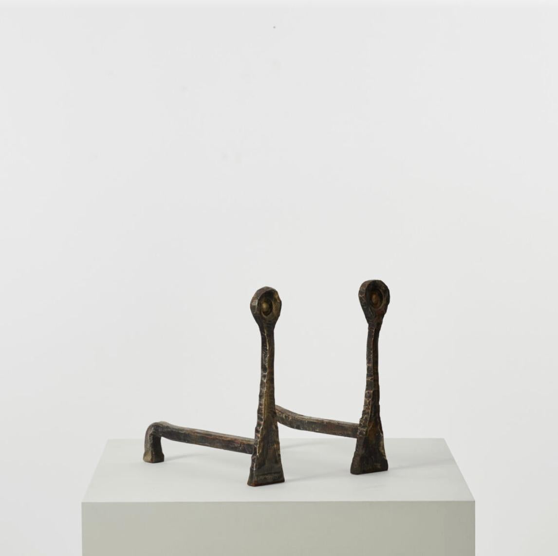 Diese eher brutalistisch geformten Andirons haben keine Vorderbeine, sondern eine dreieckige Basis, die sich bis zur Spitze hin verlängert und mit einer abgerundeten Form gekrönt ist. 

Die Andirons sind in einem guten Vintage-Zustand mit