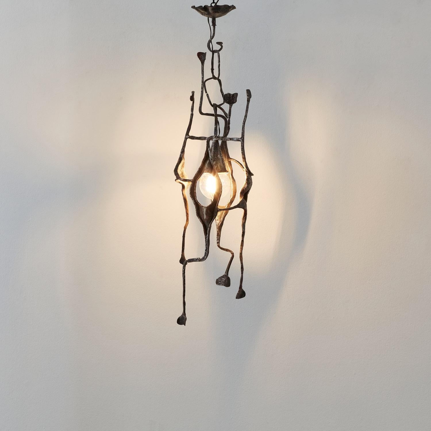 Shaped to evoke the foliated casing of a pod, the Baccello del Seme chandelier frames light as if it were a seed within. Buds and stem-like forms are clutched by a ceiling hook in this bouquet of iron. An asymmetric arrangement of form, light