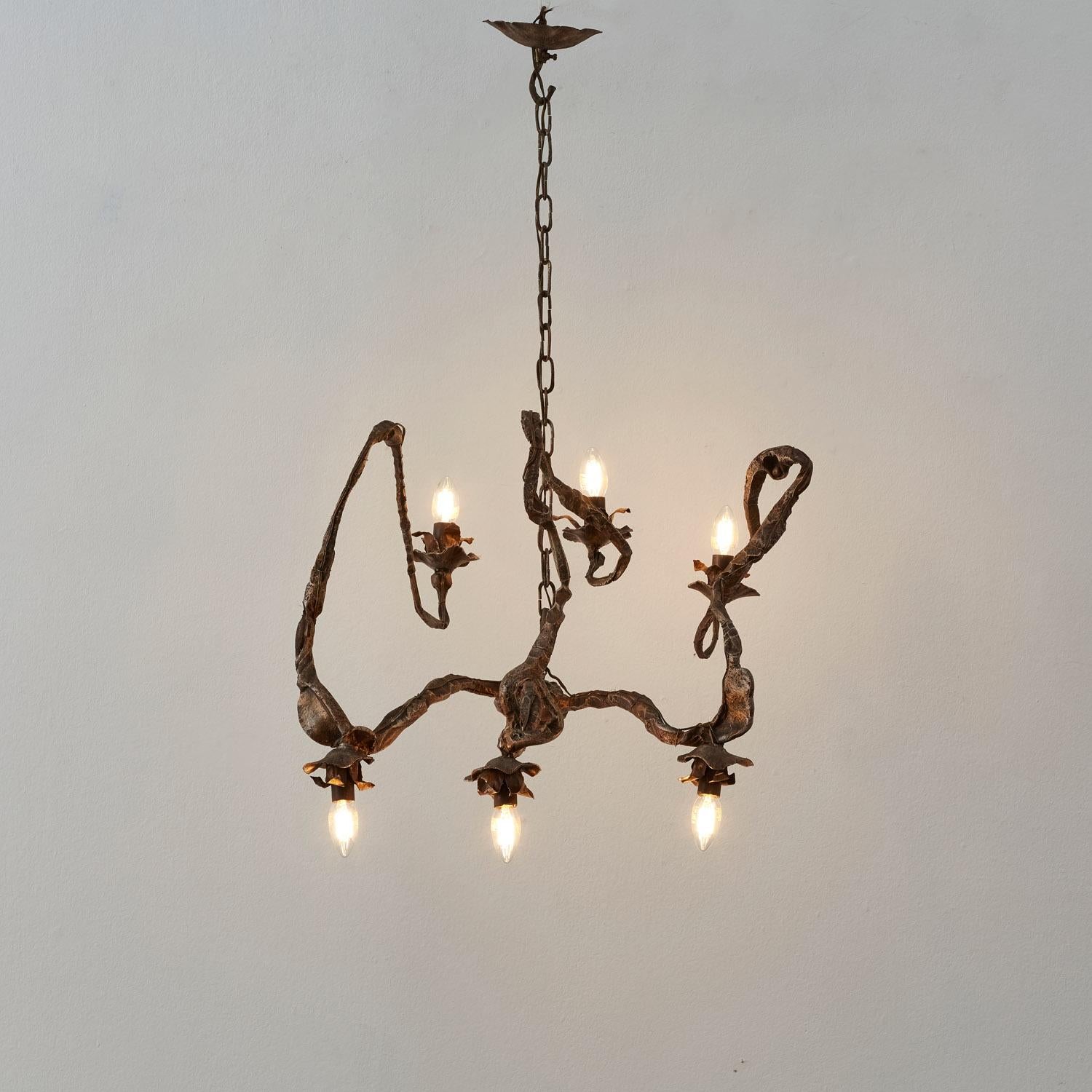 Questo lampadario in ferro battuto si attorciglia come una vite vivente, con i suoi bracci scultorei che si snodano in sei coppe simili a fiori. La patina del tempo arricchisce la sua forma organica con profondità e carattere.

Il pezzo è in buone